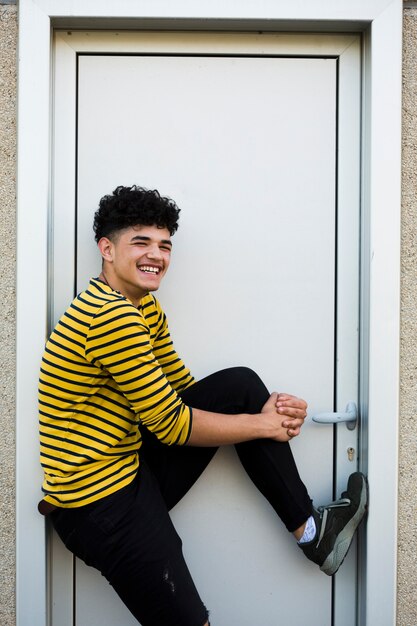 Laughing teenager in bright shirt standing in doorway