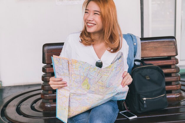 Laughing traveler with map on bench