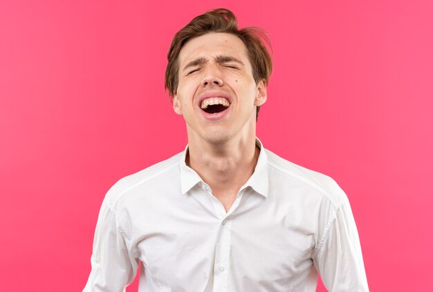 Laughing with closed eyes young handsome guy wearing white shirt isolated on pink wall