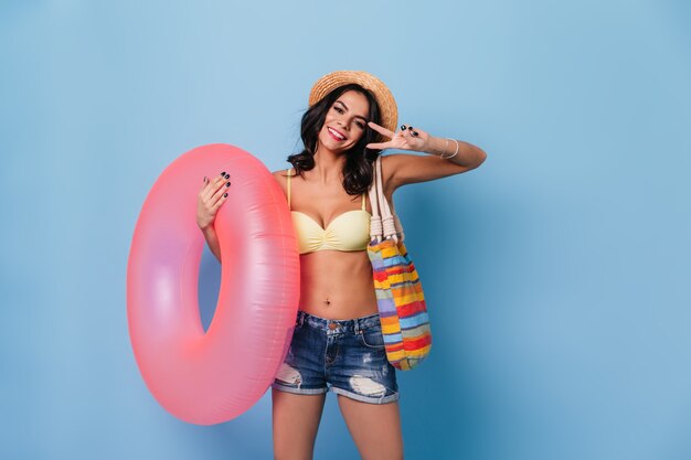 Laughing woman in denim shorts showing peace sign