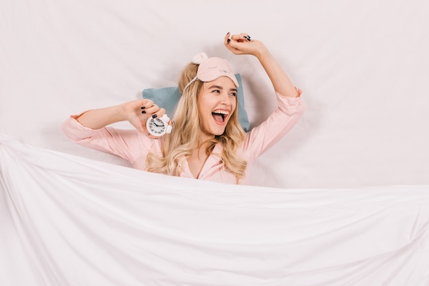 無料写真 ベッドに横たわっている睡眠マスクで笑う女性
