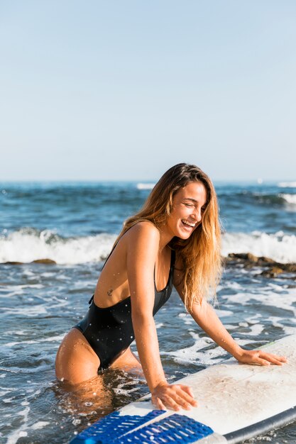 Laughing woman leaning on surfboard