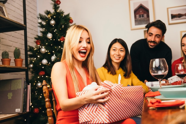 Laughing woman opening gift box at christmas dinner