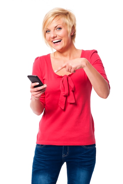 Laughing woman pointing on mobile phone