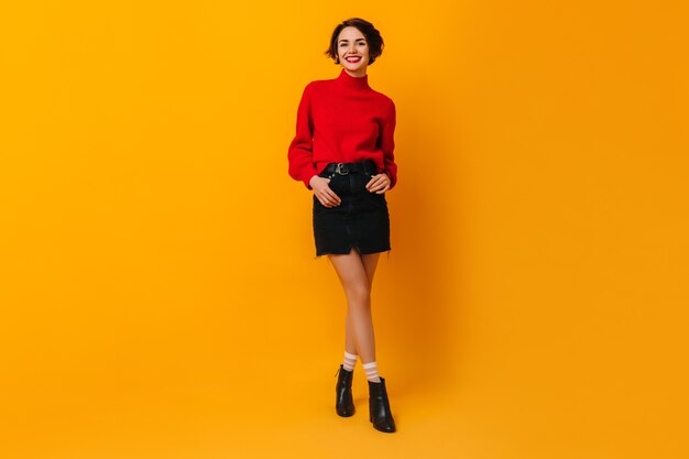 Laughing woman in short skirt standing with hands in pockets