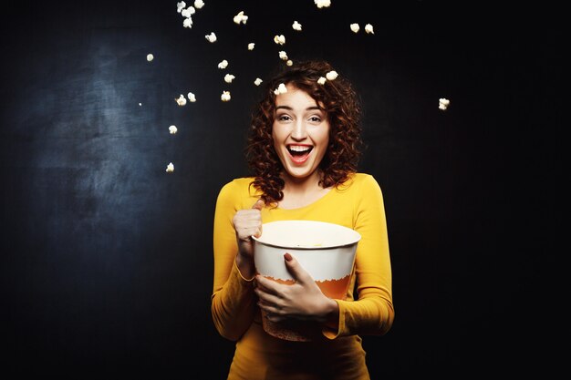 Laughing woman throwing up popcorn up in the air