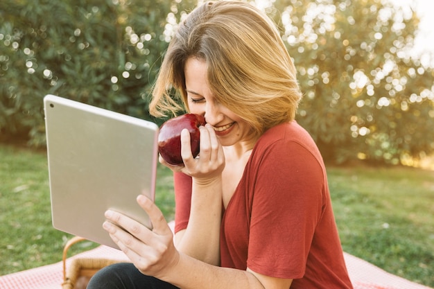 Laughing woman with apple using tablet