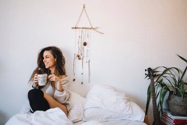 Laughing woman with coffee on bed