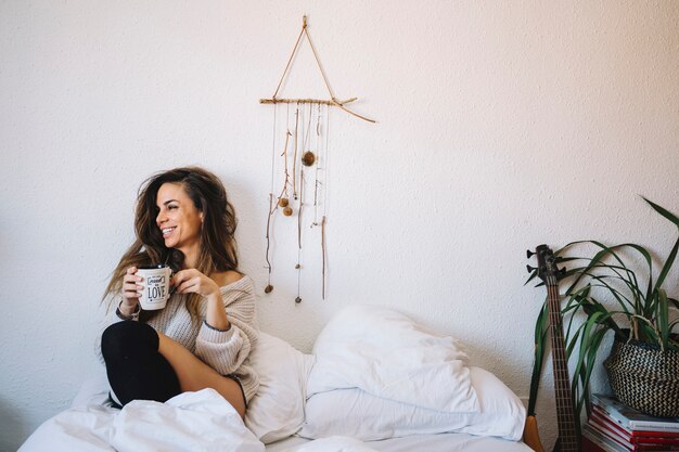 Laughing woman with coffee on bed