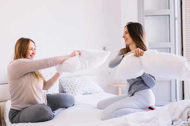 laughing women fighting with pillows