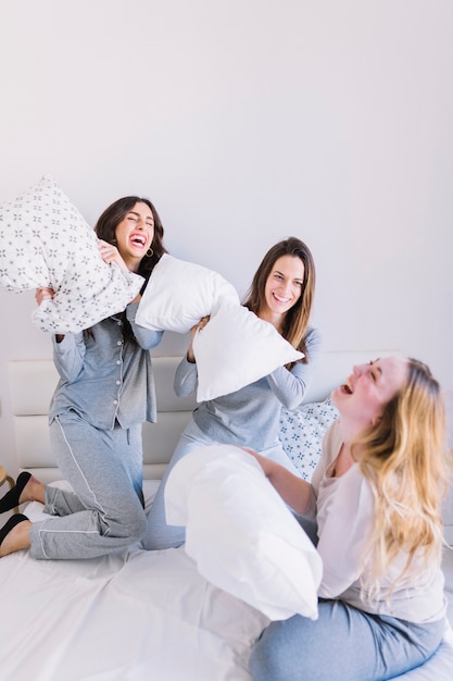 Laughing women fighting with pillows