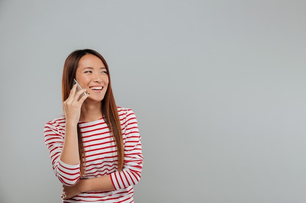 Laughing young asian woman talking by phone