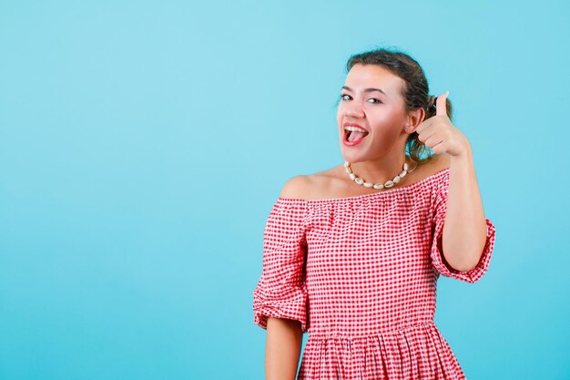 Laughing young girl is showing perfect gesture on blue background