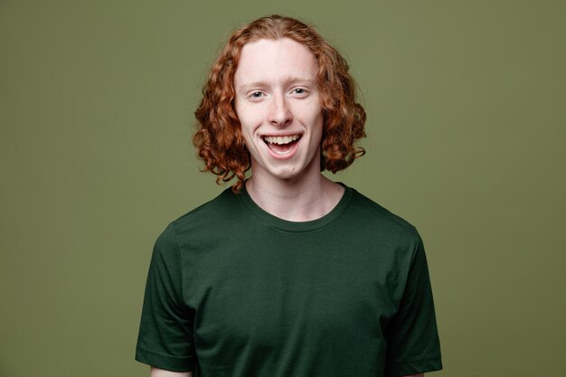 Laughing young handsome guy wearing green t shirt isolated on green background