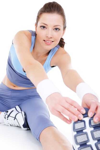 Free photo laughing young woman doing physical stretching on the floor