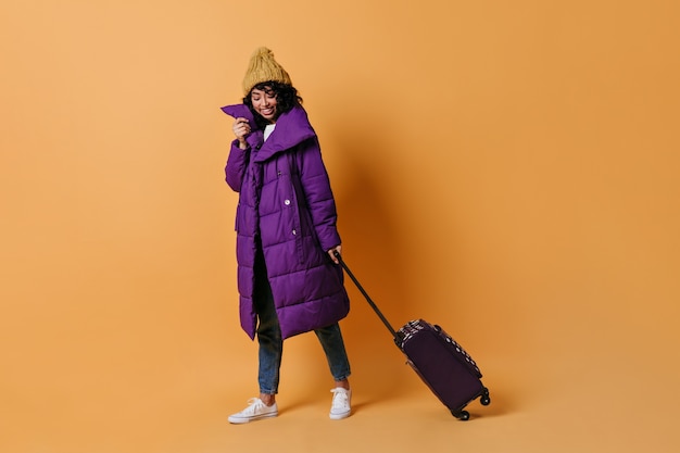 Laughing young woman posing with valise