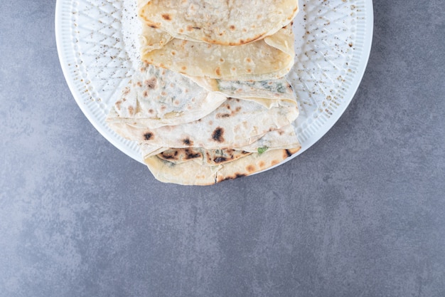 Lavash and gutab on a plate on marble table.