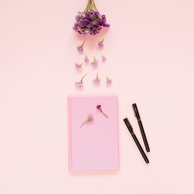 핑크 책과 컬러 배경에 두 개의 펠트 펜 위에 라벤더 꽃