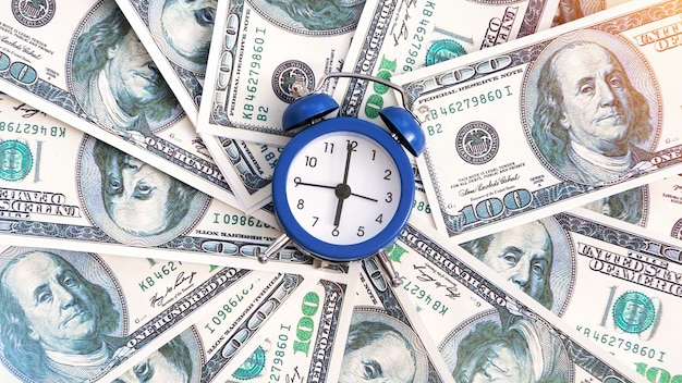 Free photo a layer of money with clock in the center. finance idea