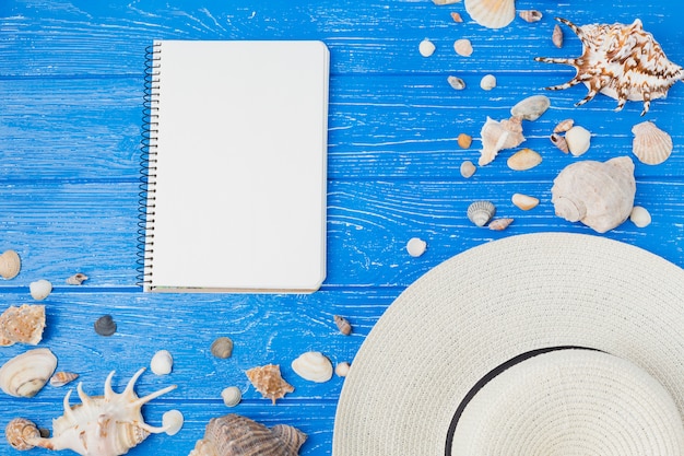 Free photo layout of seashells and hat near notepad