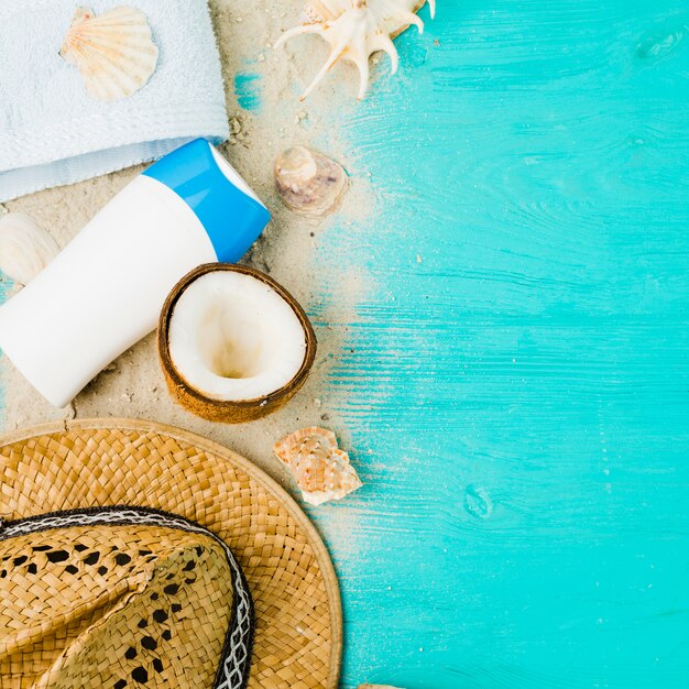 Layout of seashells near hat and coconut among sand