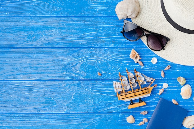 Layout of seashells near toy ship and sunglasses with hat