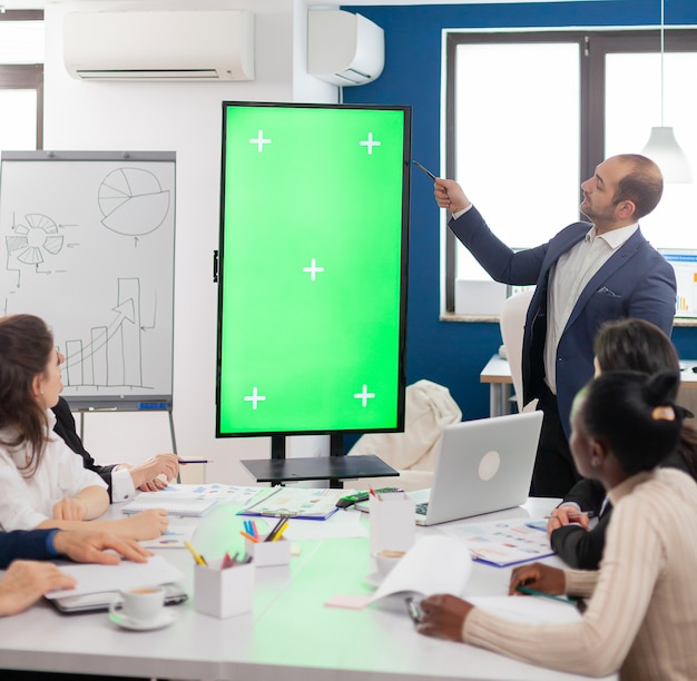 Leader of company presenting financial plan using mockup display in front of diverse team brainstorming