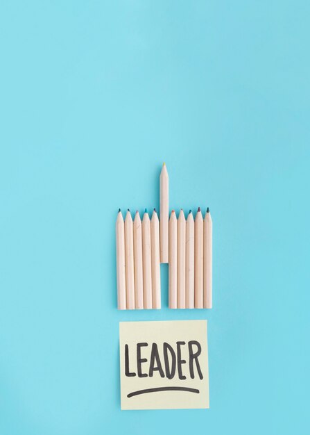 Leader text on adhesive note with row of colored pencil on blue backdrop