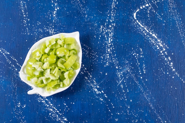 Free photo leaf-shaped plate of sliced green bell peppers on marble surface