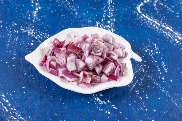 Leaf-shaped plate of sliced purple onions on marble surface