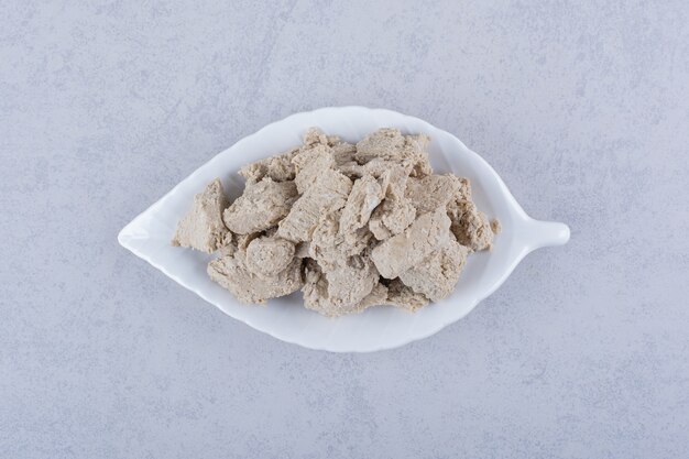 Leaf-shaped plate of tasty sunflower halva on stone.