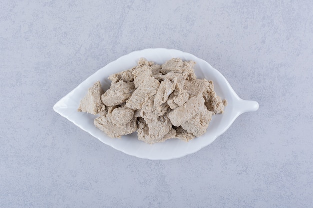 Leaf-shaped plate of tasty sunflower halva on stone.