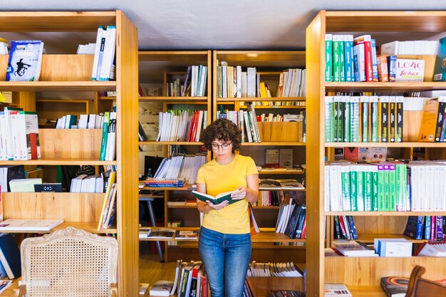 Learning lady standing between bookcases