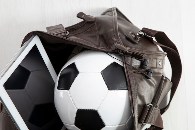 Leather bag packed with football and tablet