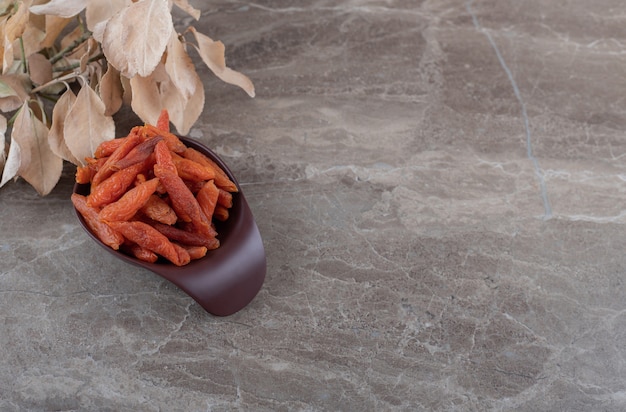 Leaves and dried fruit in the bowl on the marble surface