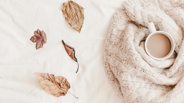 Free photo leaves near hot drink in plaid on bedsheet