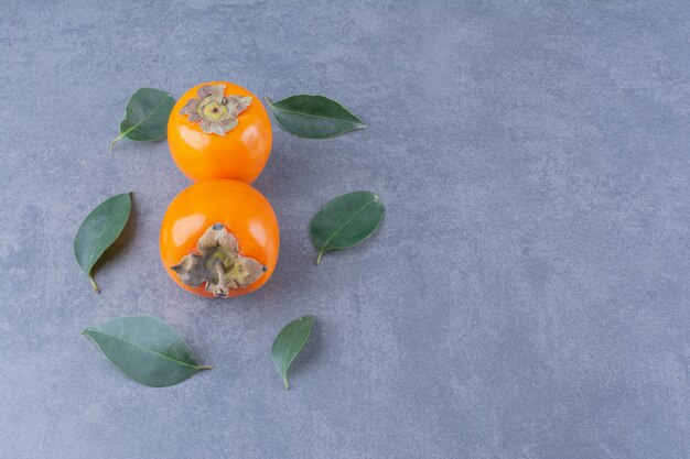 Leaves and persimmon fruits on the dark surface