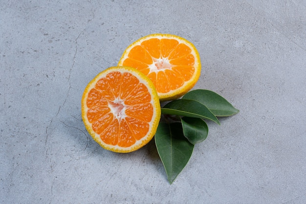 Free photo leaves and tangerines slices bundled together on marble background.