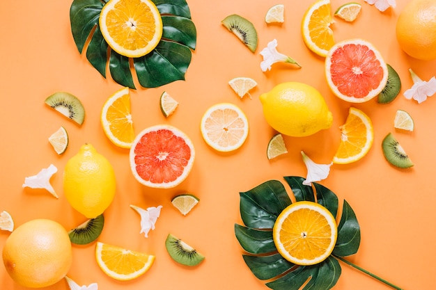 Foglie con arance vicino frutta e fiori