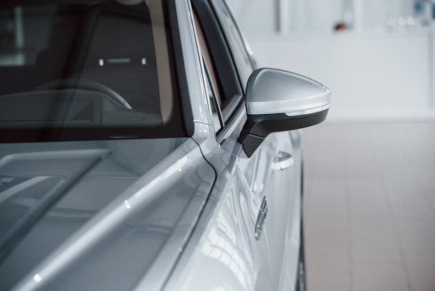 Left side. Particle view of modern luxury white car parked indoors at daytime