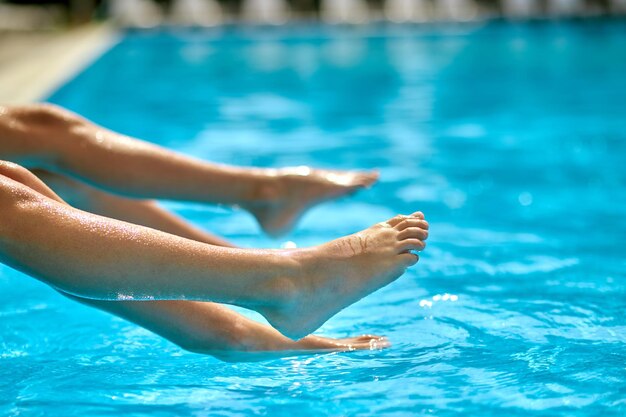 Legs of children sitting on edge of pool