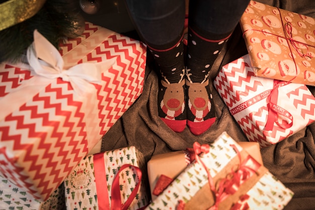 Legs in Christmas socks between present boxes 