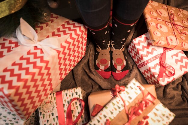 Legs in Christmas socks between present boxes 