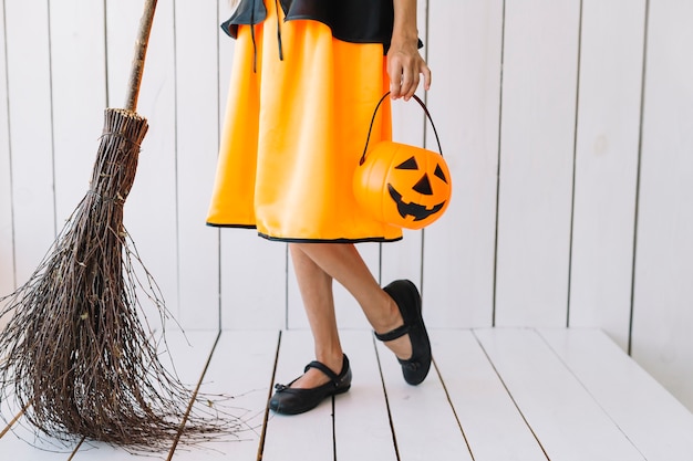 Legs of girl holding Halloween basket and broom