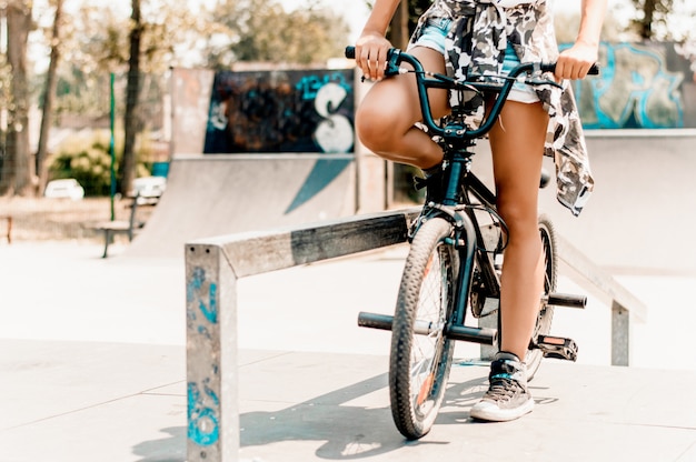 Legs of pretty girl sitting on bicycle in urban environment