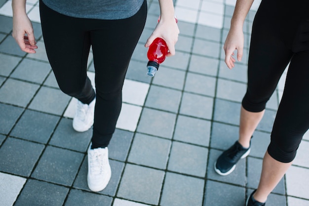 Legs of sporty women with red drink