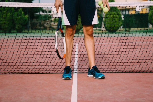 Legs of tennis player in front of net