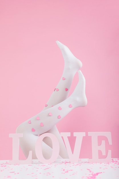 Free photo legs in tights with paper hearts near love inscription