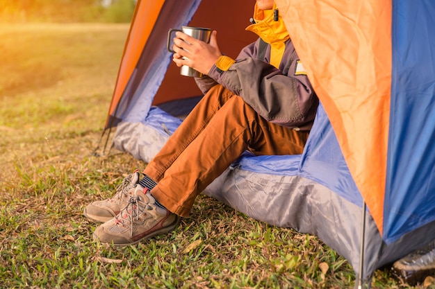 legs visible from the tent in the campsite in wild wood background