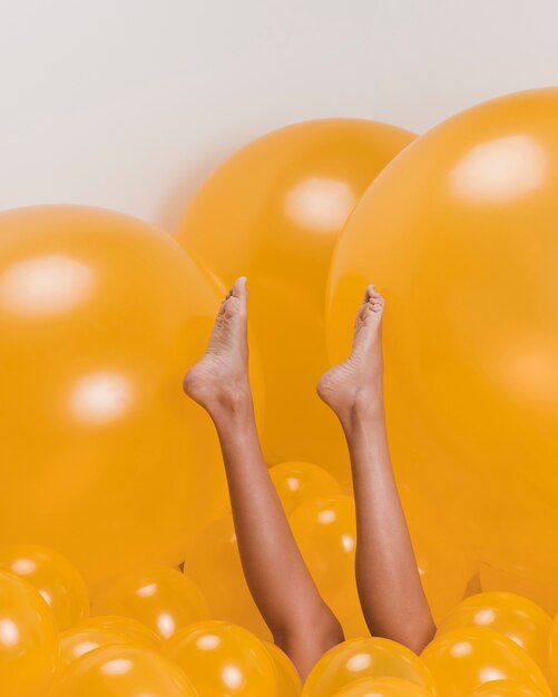 Ноги женщины между много желтых воздушных шаров